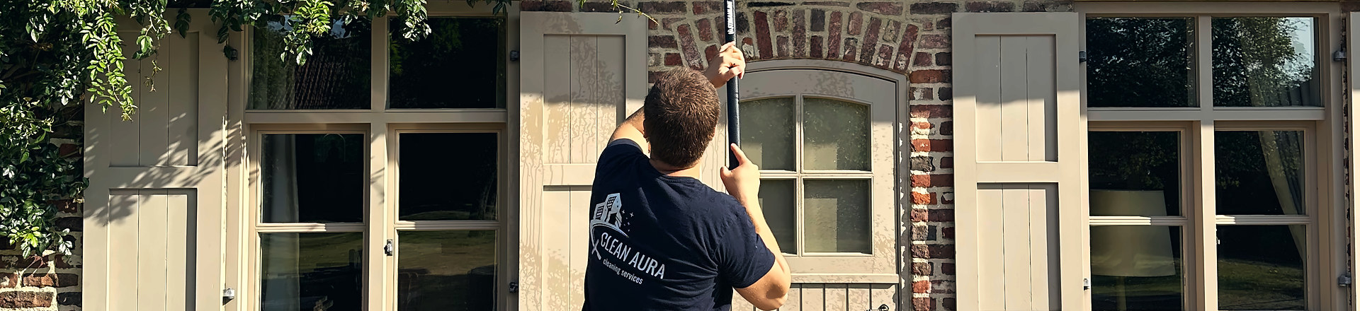 Clean Aura medewerker wast de ramen van een woning met luiken