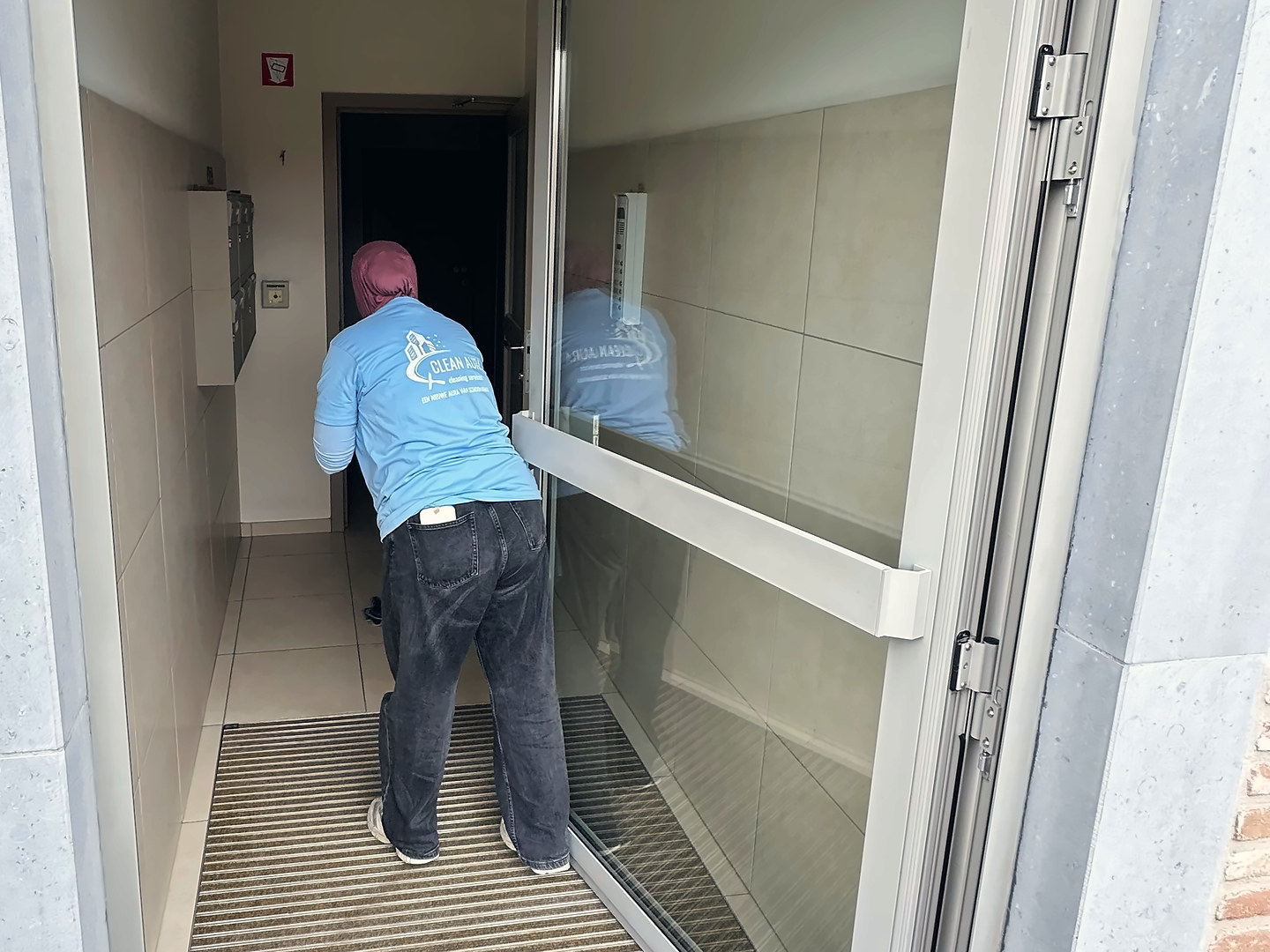 Clean Aura medewerkster reinigt de inkomhal van een appartementsgebouw