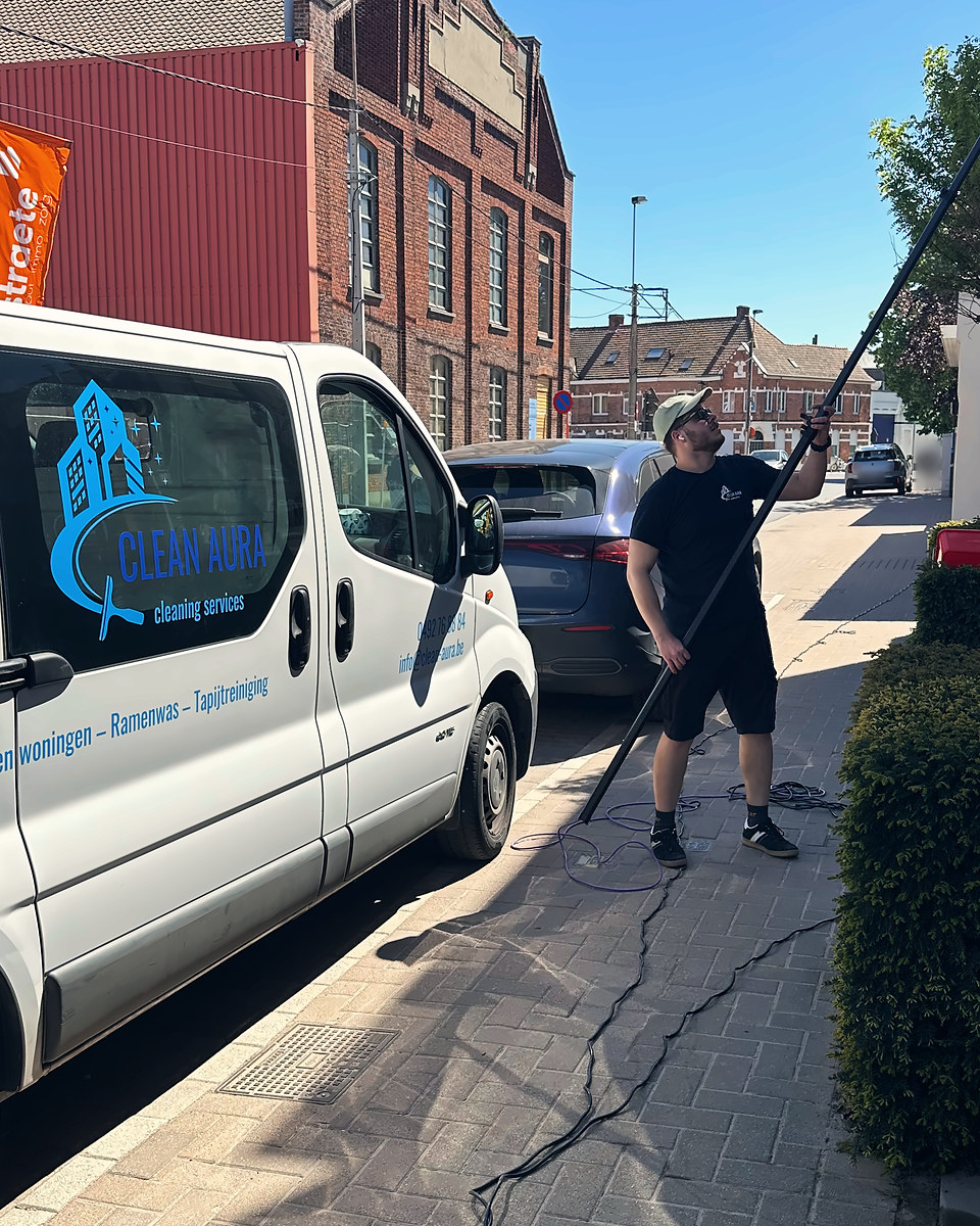 Clean Aura medewerker wast ramen met een telescoopsteel, naast de Clean Aura bestelwagen