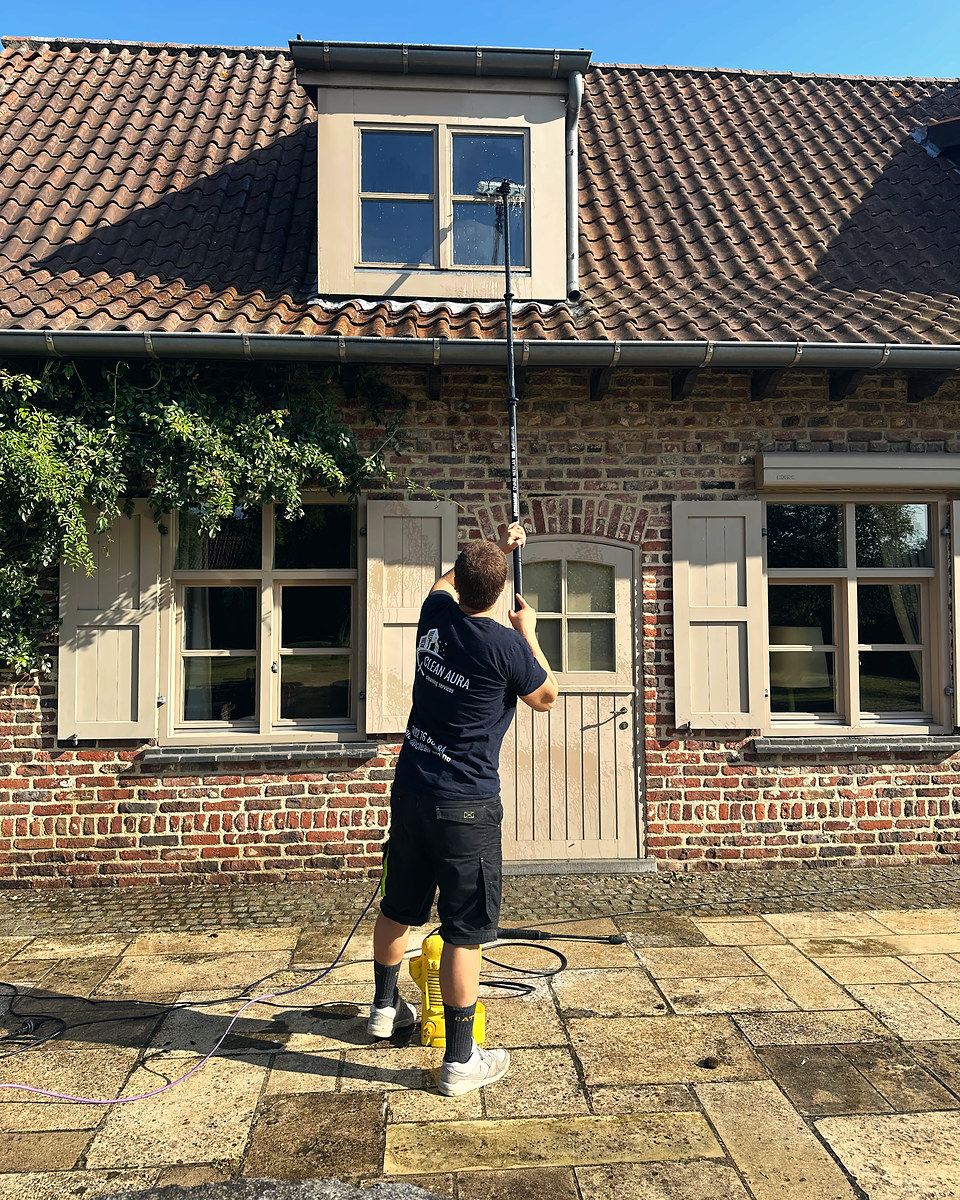 Clean Aura medewerker wast het dakkapelraam van een woning met een telescoopsteel