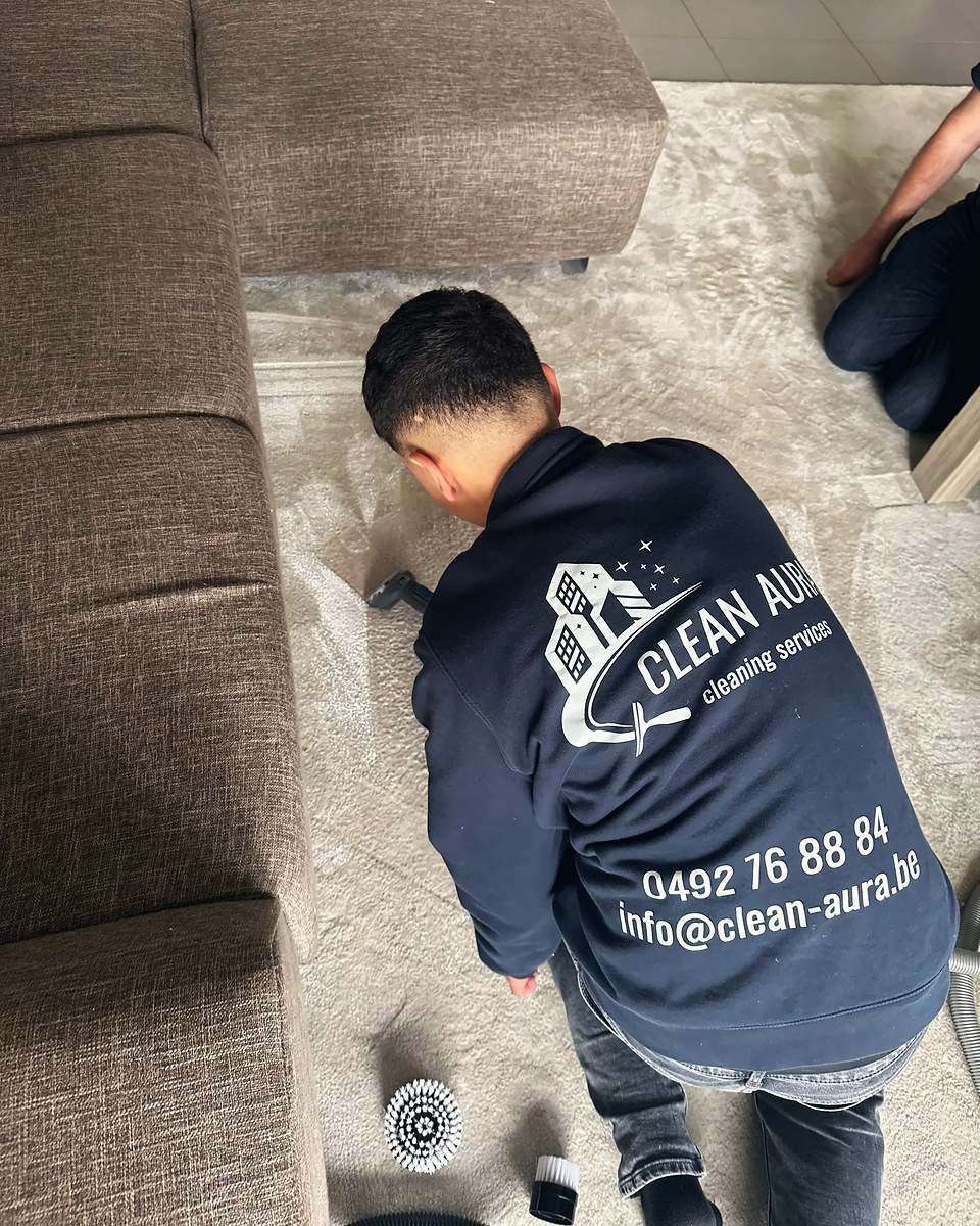 Clean Aura medewerker reinigt een vloerkleed in een woonkamer met een sproei-extractietoestel