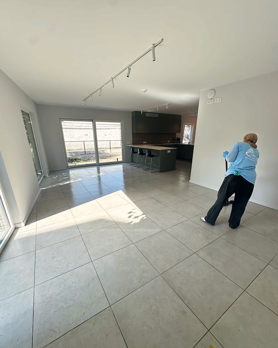 Clean Aura medewerkster dweilt de tegelvloer van een lichte, lege woning