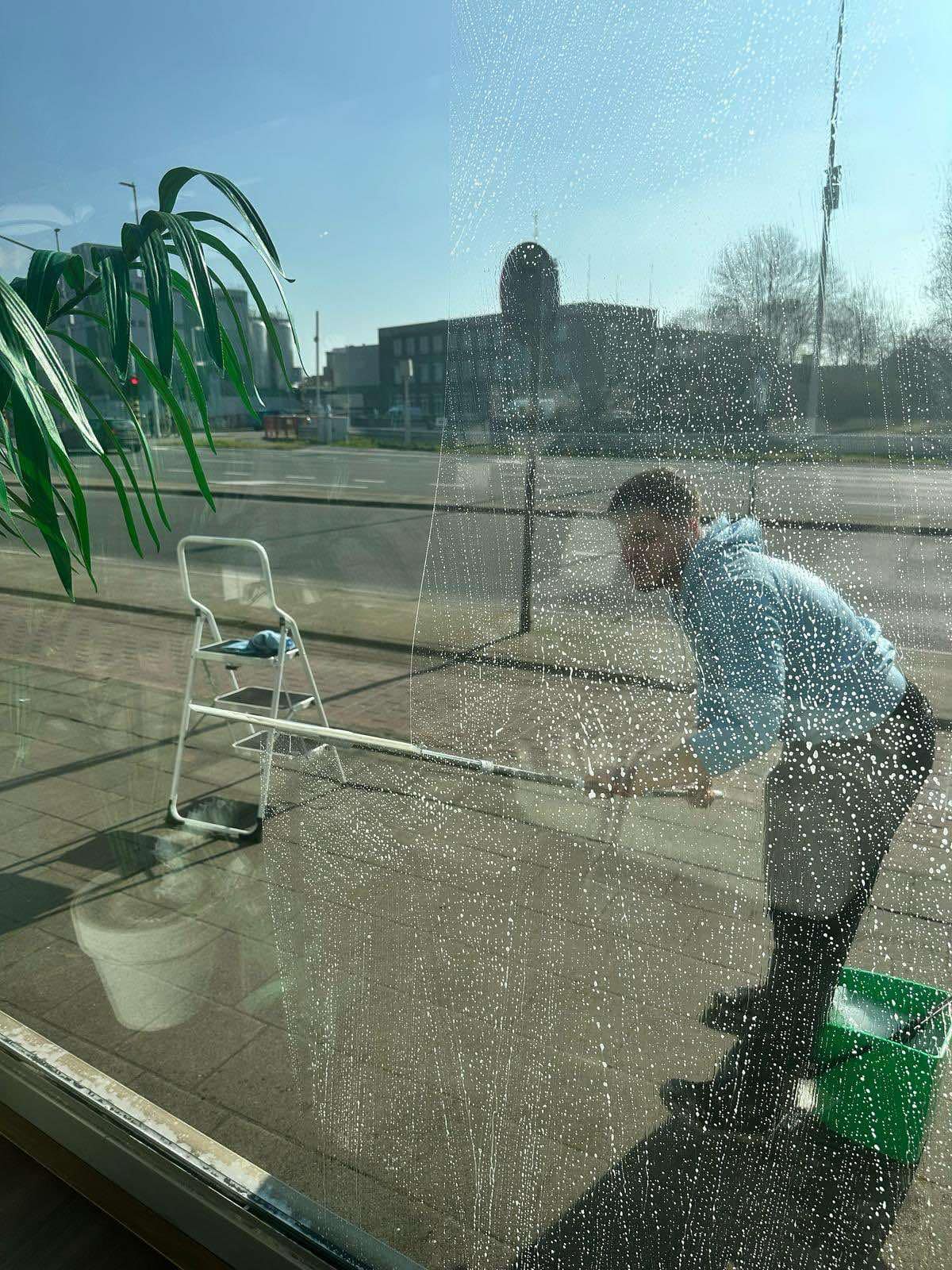 Clean Aura medewerker zeept een winkelruit in, gezien van binnenuit